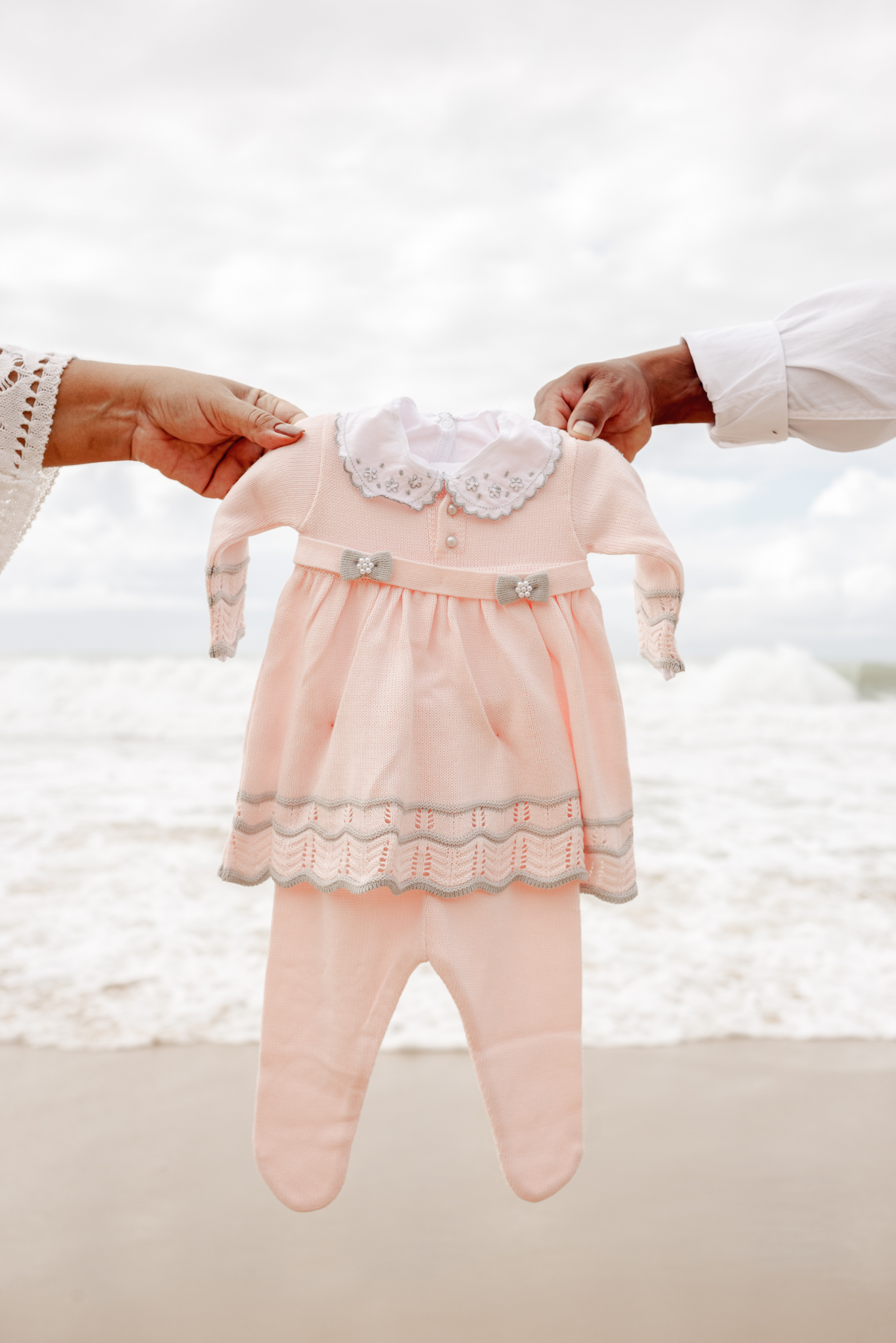 gestante na praia com roupinha do bebe